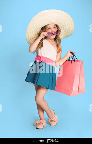 La jolie petite fille brune en tenue d'caucasien holding shopping bags Banque D'Images