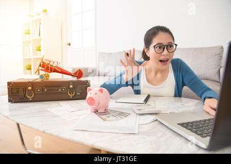 Jeune étudiante à l'aide d'un ordinateur portable à la maison à la recherche de dépôts bancaires par Internet aux particuliers heureusement trouver suffisamment d'argent pour les voyages peut célébrer sa Banque D'Images