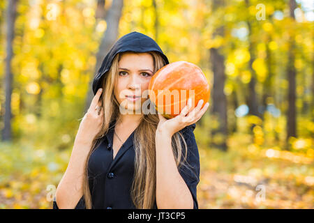 Portrait d'une belle blonde young woman holding pumpkin en forêt. Journée de l'Halloween. Banque D'Images