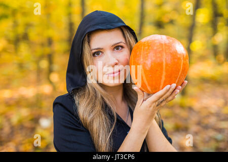 Portrait d'une belle blonde young woman holding pumpkin en forêt. Journée de l'Halloween. Banque D'Images