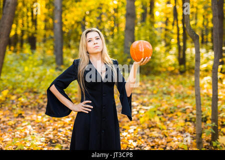 Portrait d'une belle blonde young woman holding pumpkin en forêt. Journée de l'Halloween. Banque D'Images