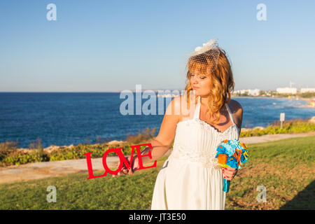 Bride holding bouquet et du mot amour Banque D'Images