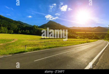 Sunny Road - peu d'arbres sur une colline près de la prairie mountain route asphaltée dans la lumière du soir Banque D'Images