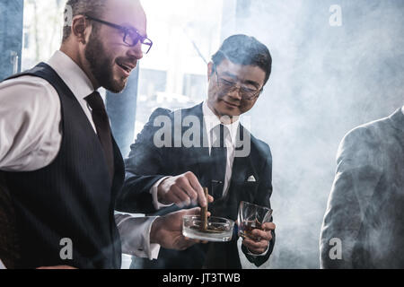 Groupe d'hommes d'affaires multiethniques de fumer et de boire le whisky à l'intérieur, réunion de l'équipe de l'entreprise Banque D'Images