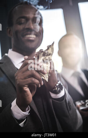 Close-up view of smiling businessman confiant cigare avec éclairage billets dollar Banque D'Images