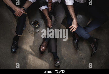Cropped shot de groupe d'hommes assis sur le plancher ensemble Banque D'Images