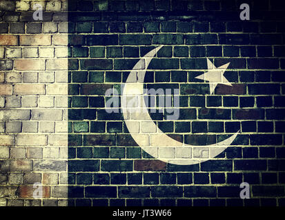 Drapeau pakistanais s'est évanoui sur un vieux mur de brique avec une vignette sombre en arrière-plan Banque D'Images