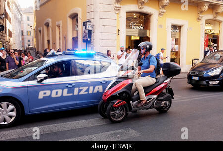Rome Italie Juillet 2017 - Scooter rider adoptée par une voiture de police polizia avec lumière bleue clignotant dans les rues de ville photographie prise par Simon Dack Banque D'Images