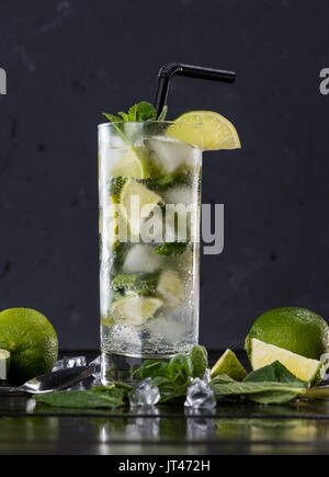 Vue rapprochée de mojito cocktail dans le verre, des tranches de citron vert et de menthe sur noir, cocktails concept Banque D'Images