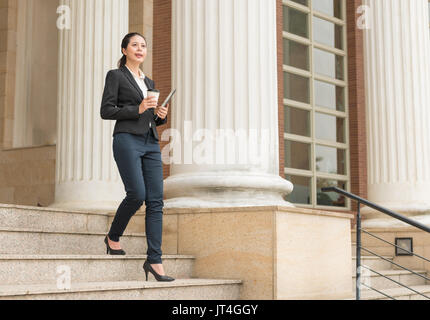 Longueur totale de l'image d'affaires professionnel woman holding digital tablet et café tasse de papier aller au travail à pied de la cour et de penser à company cl Banque D'Images