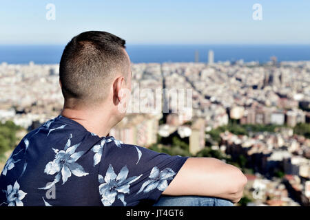 Libre d'un jeune homme de race blanche en haut d'une colline, l'observation de la ville de Barcelone, en Espagne, au-dessous de lui Banque D'Images