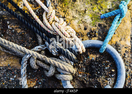 Des cordes attachées à l'anneau métallique dans un port, texture grunge Banque D'Images