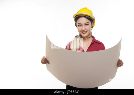 Young Asian woman architect avec chemise rouge et jaune casque de sécurité tout en souriant la lecture de bleus. les gens de l'occupation industrielle concept Banque D'Images