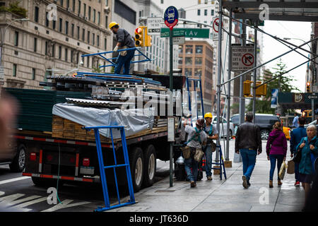 NEW YORK, USA - Le 13 octobre 2016. Peu de gens avec chariot de déchargement des matériaux de construction comme d'échafaudages et d'autre structure sur la 5e Avenue, New York. Banque D'Images