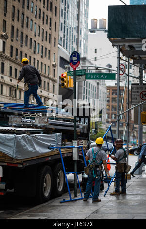 NEW YORK, USA - Le 13 octobre 2016. Peu de gens avec chariot de déchargement des matériaux de construction comme d'échafaudages et d'autre structure sur la 5e Avenue, New York. Banque D'Images