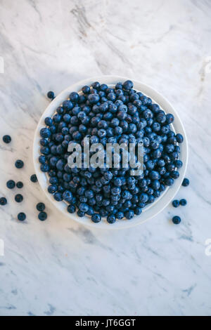 Les bleuets frais biologiques dans un bol blanc sur la table de marbre blanc Banque D'Images