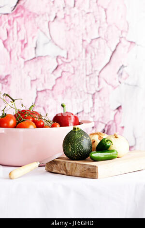 Les tomates dans une cocotte, entouré par des tons roses Banque D'Images