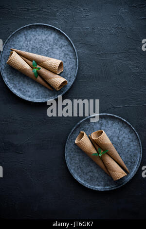 Des cornets de crème glacée vide sur une plaque, sur un fond gris ardoise Banque D'Images