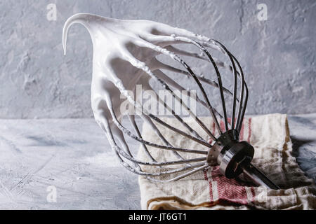 Processus de la cuisson de la meringue. Les blancs d'œufs fouettés sur fouet mélangeur sur lin gris serviette sur fond de texture. Pâtisseries Dessert concept. Close up Banque D'Images