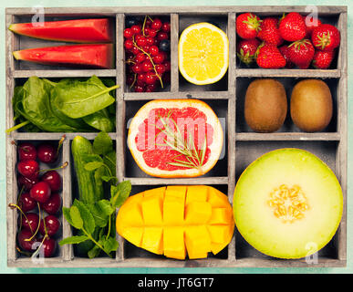 Les légumes et fruits dans un coffret en bois pour végétalien, sans gluten, gay-friendly, propre alimentation et régime alimentaire des matières premières. Fond bleu et Vue de dessus Banque D'Images