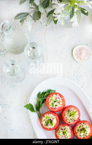 Taboulé Quinoa tomates farcies servies avec du vin blanc. Photographié sur un fond de plâtre blanc. Banque D'Images