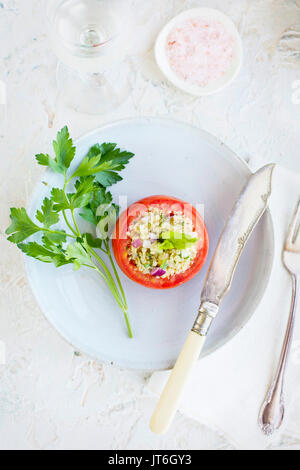 Taboulé Quinoa tomates farcies servies avec du vin blanc. Photographié sur un fond de plâtre blanc. Banque D'Images