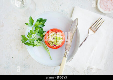 Taboulé Quinoa tomates farcies servies avec du vin blanc. Photographié sur un fond de plâtre blanc. Banque D'Images