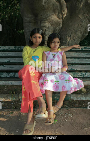 Deux soeurs dans humeur pensive assise sur un banc de parc Banque D'Images