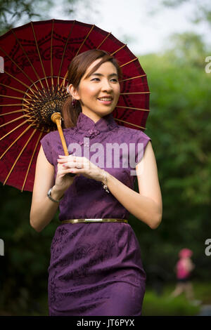 Cheongsam chinois femme portant une robe chinoise traditionnelle avec parapluie. Banque D'Images