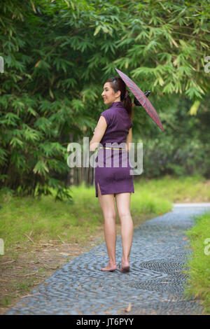 Cheongsam chinois femme portant une robe chinoise traditionnelle avec parapluie. Banque D'Images