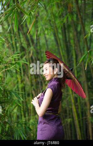 Cheongsam chinois femme portant une robe chinoise traditionnelle avec parapluie. Banque D'Images