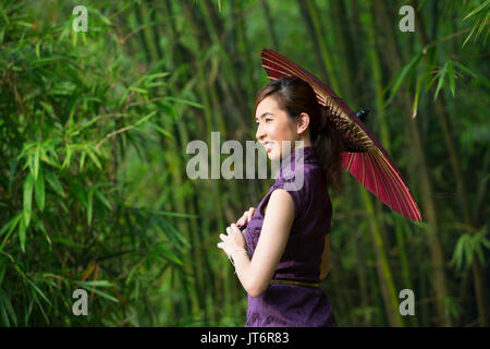 Cheongsam chinois femme portant une robe chinoise traditionnelle avec parapluie. Banque D'Images