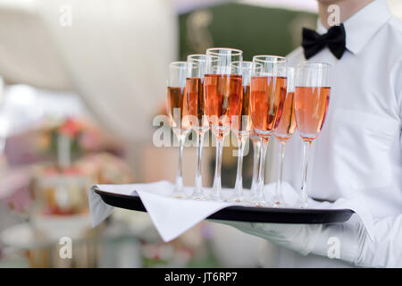 Petit waiter holding tray with glasses Banque D'Images