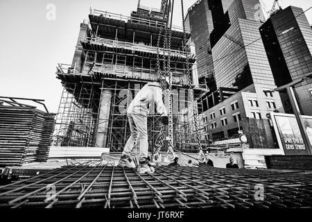 Tel-Aviv - 9 décembre, 2016 : un travailleur dans un chantier de connecte le crochet de grue à rusty raccords. Banque D'Images