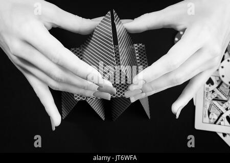 Femme mains assemblage château de cartes. Photo en noir et blanc. Le jeu, casino, fortune et chance thème Banque D'Images