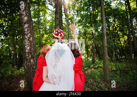 Mariée douce et belles demoiselles ont beaucoup de plaisir dans le parc le long d'une journée de mariage. Banque D'Images