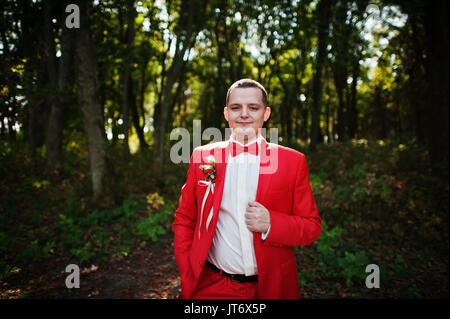 Portrait d'un beau palefrenier en rouge tuxedo posant seul dans la forêt. Banque D'Images