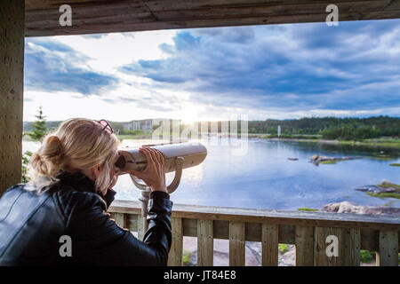 Jeune femme regardant la nature extraordinaire par un binoculaire dans une tour d'observation au Québec, Canada. Banque D'Images