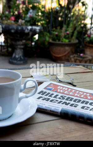 Une copie de l'hebdomadaire britannique sur une table en Californie. Un journal de réseau des expatriés anglais en Amérique latine avec une tasse de thé et d'une paire de lunettes de lecture Banque D'Images