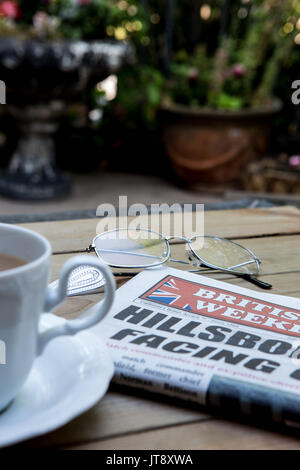 Une copie de l'hebdomadaire britannique sur une table en Californie. Un journal de réseau des expatriés anglais en Amérique latine avec une tasse de thé et d'une paire de lunettes de lecture Banque D'Images