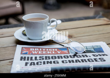 Une copie de l'hebdomadaire britannique sur une table en Californie. Un journal de réseau des expatriés anglais en Amérique latine avec une tasse de thé et d'une paire de lunettes de lecture Banque D'Images