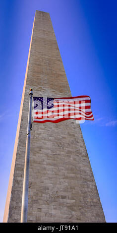 Un drapeau américain va à l'avant du Monument de Washington à Washington, D.C. Etats-unis. Banque D'Images