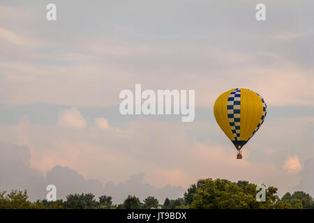 À motifs jaune et bleu hot air balloon flotte entre les montagnes dans un beau ciel au crépuscule de Warren County Fair de l'agriculteur sur 8/1/17 Banque D'Images