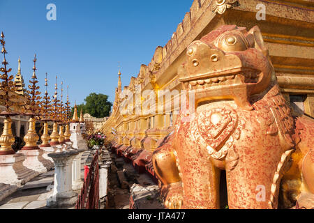 La plate-forme inférieure de la Pagode Shwezigon bouddhiste dans la ville de Nyaung-U près de Bagan en Birmanie centrale avec un chinthe lion statue Banque D'Images