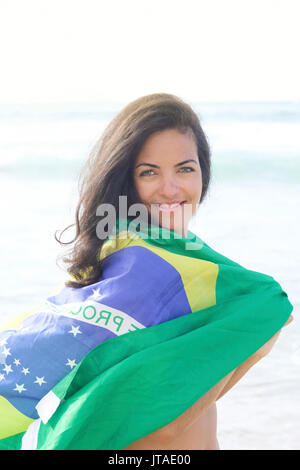 Jeune femme brésilienne de 20 à 29 ans avec un drapeau brésilien beach wrap sur une plage, Rio de Janeiro, Brésil, Amérique du Sud Banque D'Images