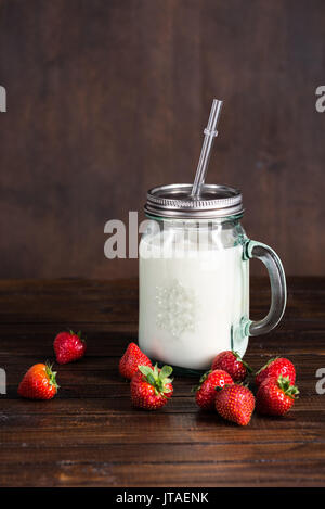 Dans la verseuse en verre de lait et de fraises fraîches sur la table en bois Banque D'Images