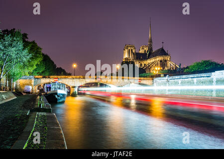Une longue exposition d'un bateau sur la Seine en passant la cathédrale Notre Dame sur une soirée dans Paris, France, Europe Banque D'Images