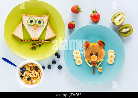 Mise à plat avec un style de façon créative le petit déjeuner des enfants aux fruits rouges et kiwi Banque D'Images