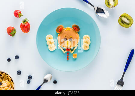 Mise à plat avec un style de façon créative le petit déjeuner des enfants aux fruits rouges et kiwi Banque D'Images