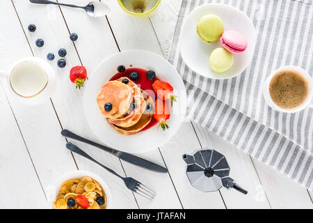 Vue de dessus de crêpes de macarons et café avec des flocons de maïs sur la table en bois